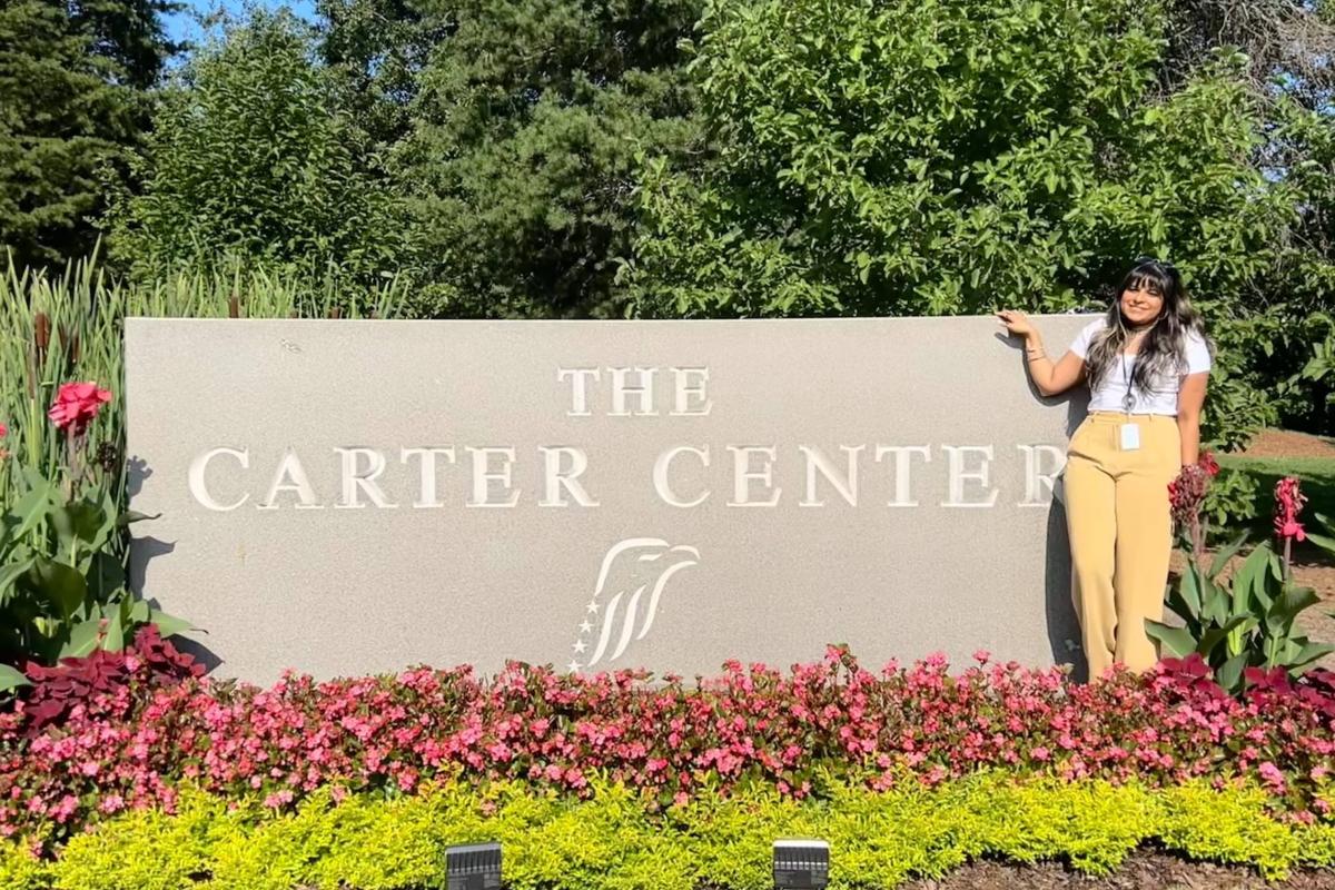 Woman near Carter Center sign and beautiful flowers