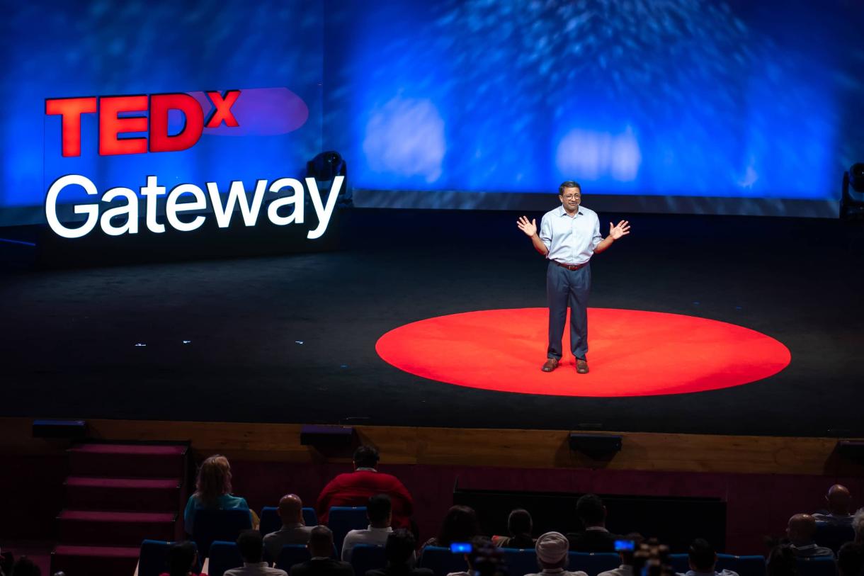 Man on stage, red circle carpet, TedX Gateway image