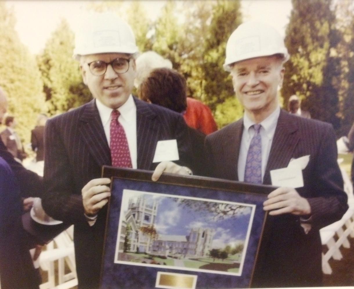 Jolel Fleishman and David Rubenstein in hard hats holding an illustration of the Sanford building