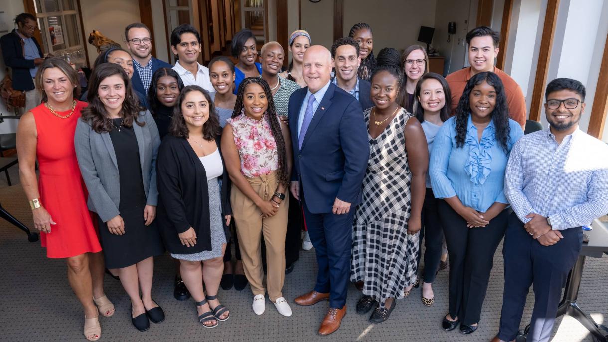 Man in suit and tie surrounded by lots of smiling students