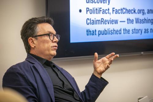 Man gesturing while speaking in front of a group.