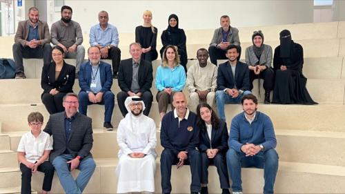 Crowd of people sitting on amphitheater seats posing for camera in group shot. 