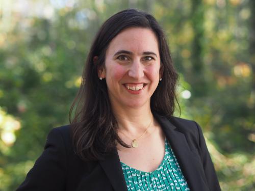 Woman portrait in black blazer and green blouse against a nature background