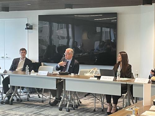 Three people sitting at table delivering panel discussion at conference. 